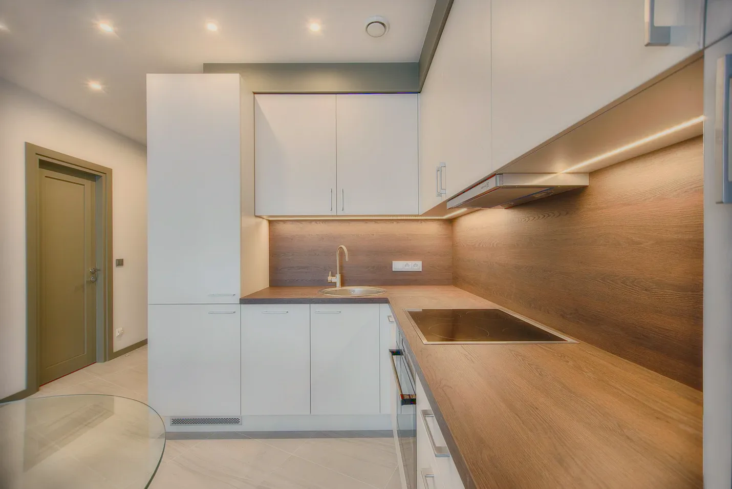 A kitchenette with white cupboards and a wooden counter.